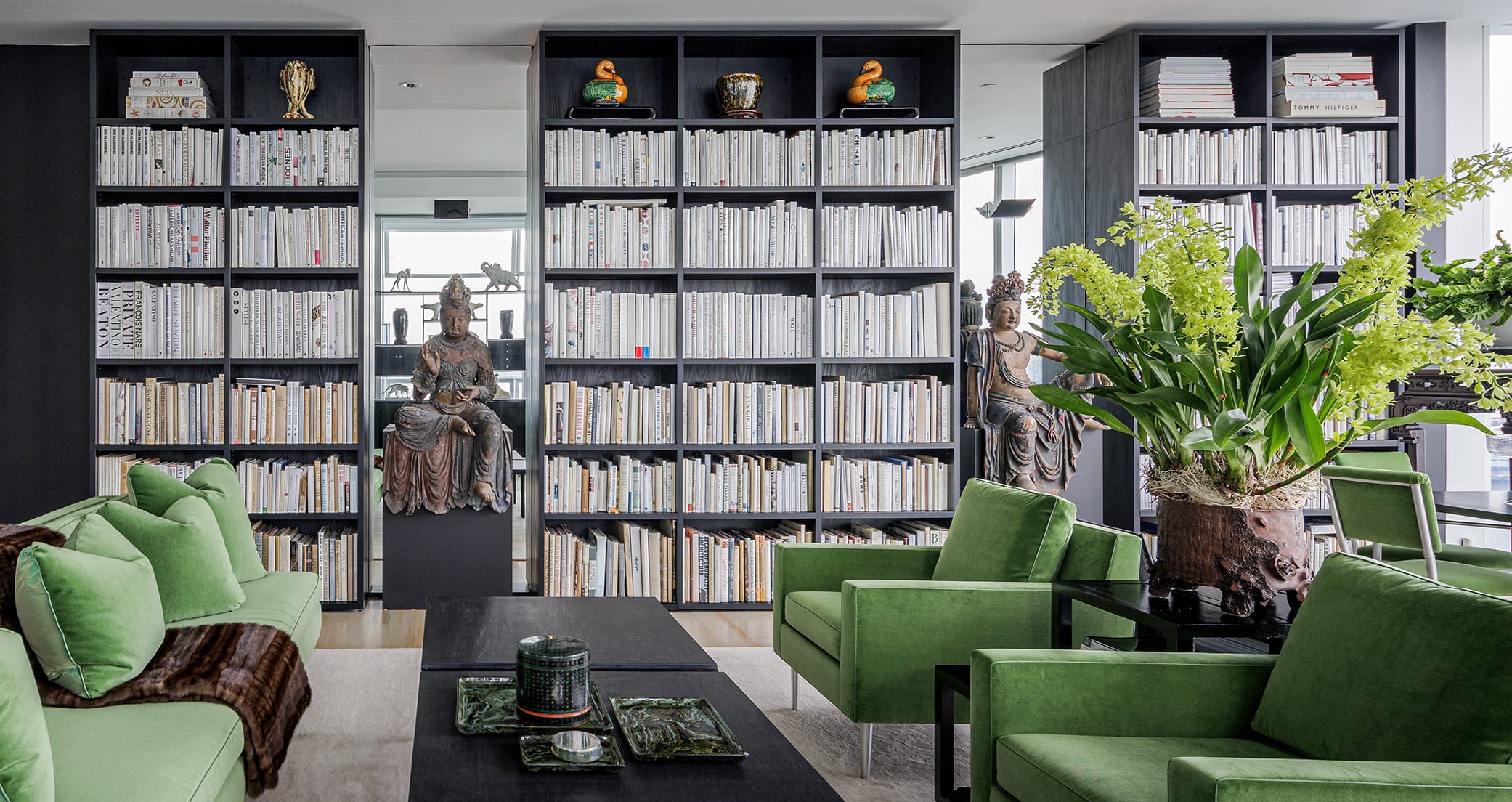 Contemporary living room with bookshelves from floor to ceiling in dark wood grain finish by California Closets