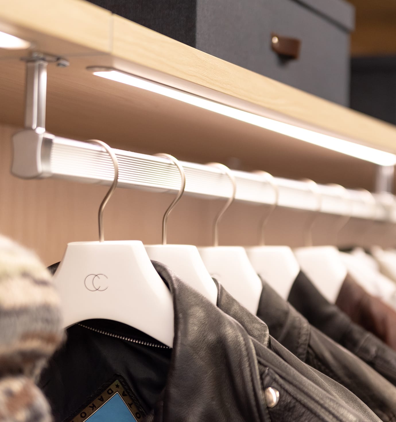 Wardrobe lighting with light wood finish clothing rail and open shelves by California Closets